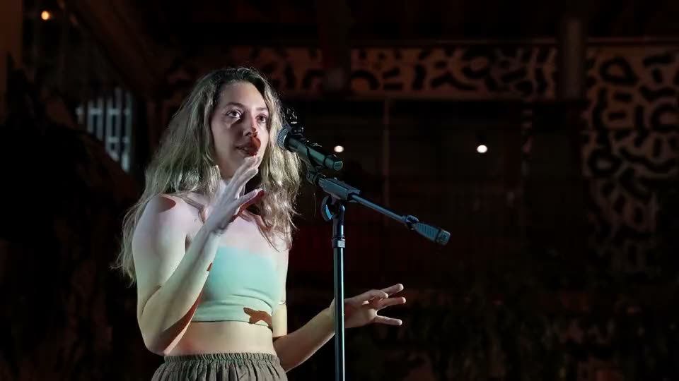 A singer performing at the mic under a spotlight