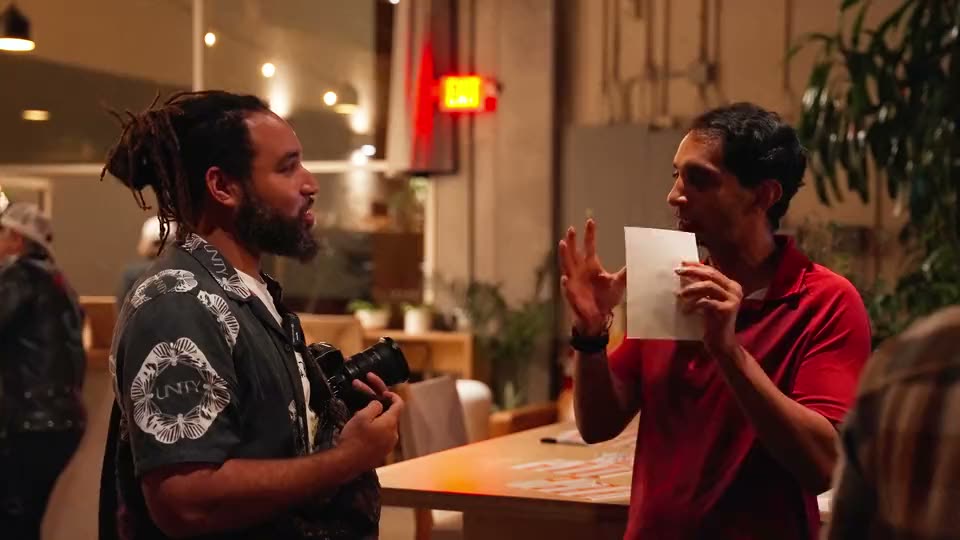 Two guests mid-conversation, one holding up a sheet of paper