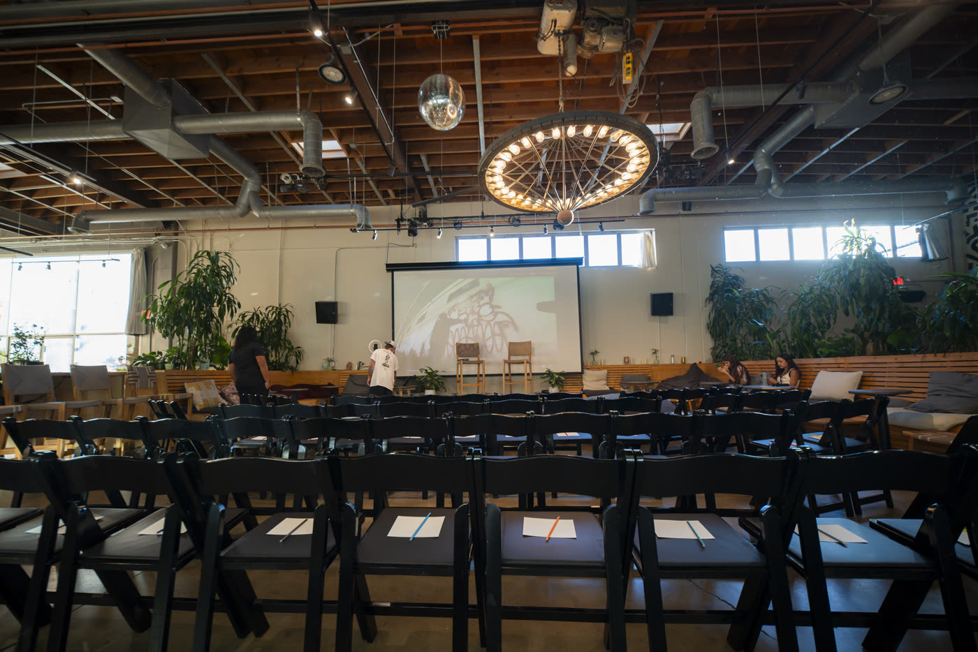 The empty room before doors: rows of chairs, each with paper and a pencil