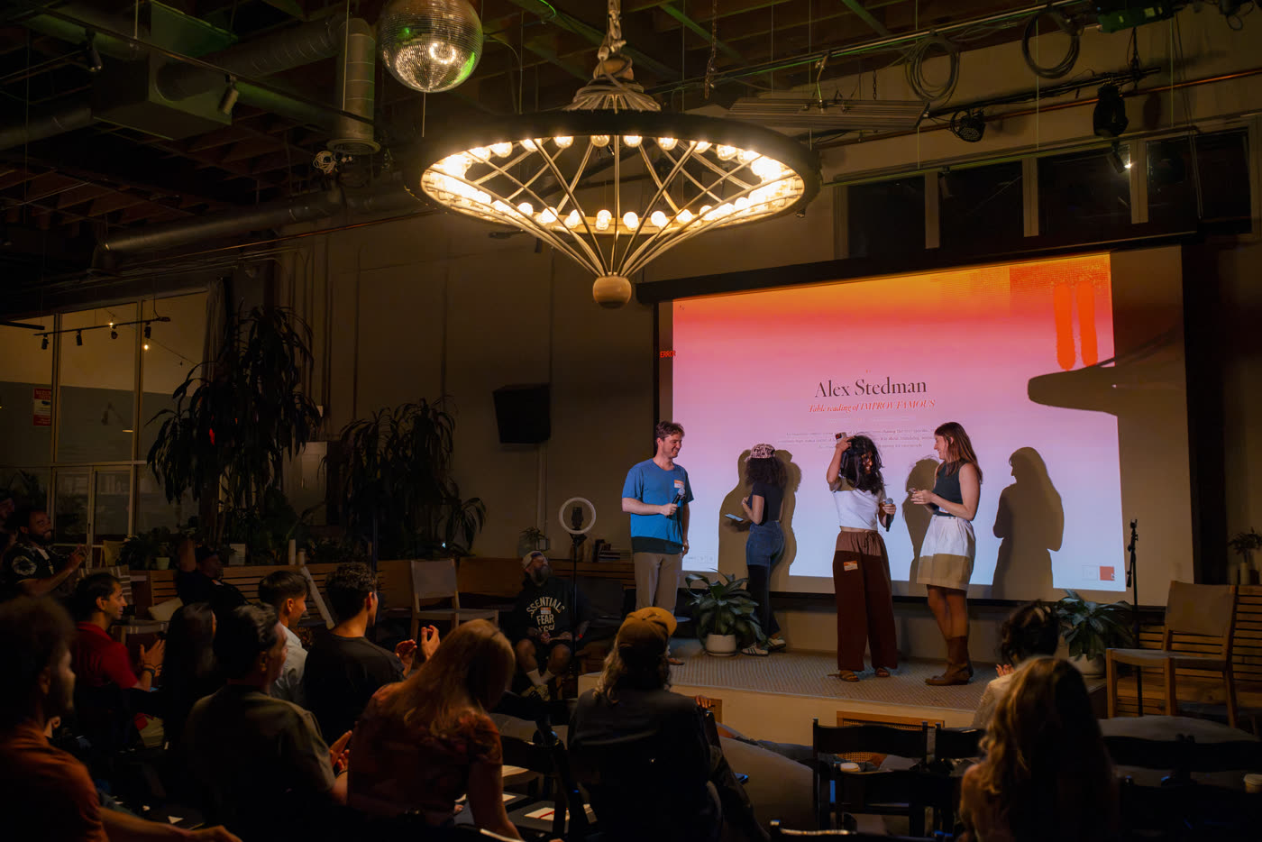 A table read on stage in front of a seated audience